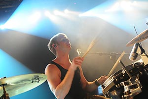 Schlagzeuger von schräg unten fotografiert im weissem Scheinwerferlicht